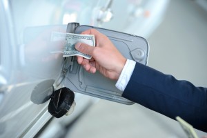 Image - hand putting money into gas tank.