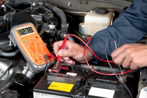 Image of a mechanic using a multi-meter to check the voltage of a car battery.