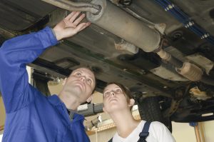 image - Mechanic and customer looking at exhaust system under car on lift