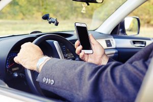 man looking at the phone while driving his car